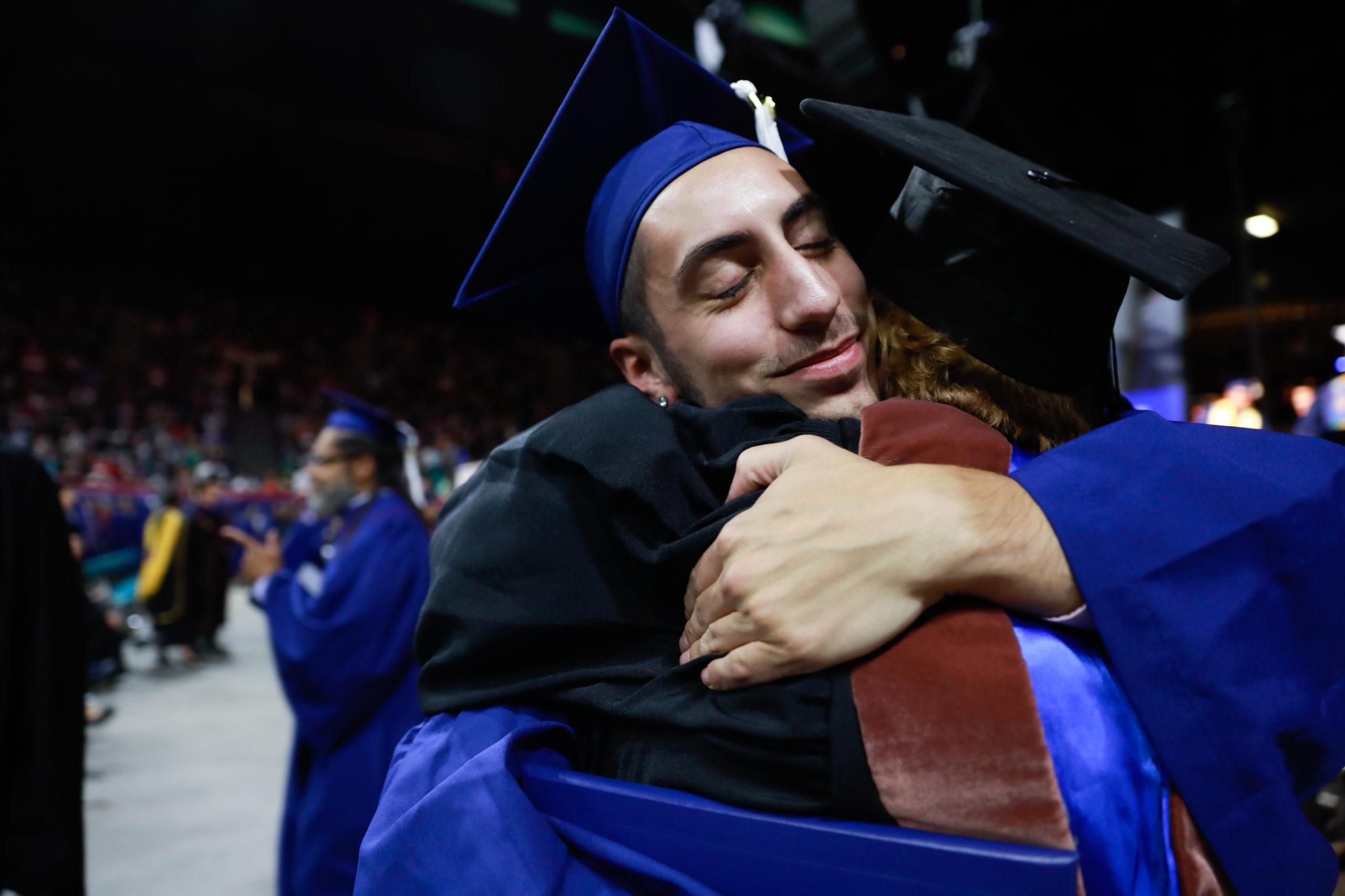 A faculty member hugs a student