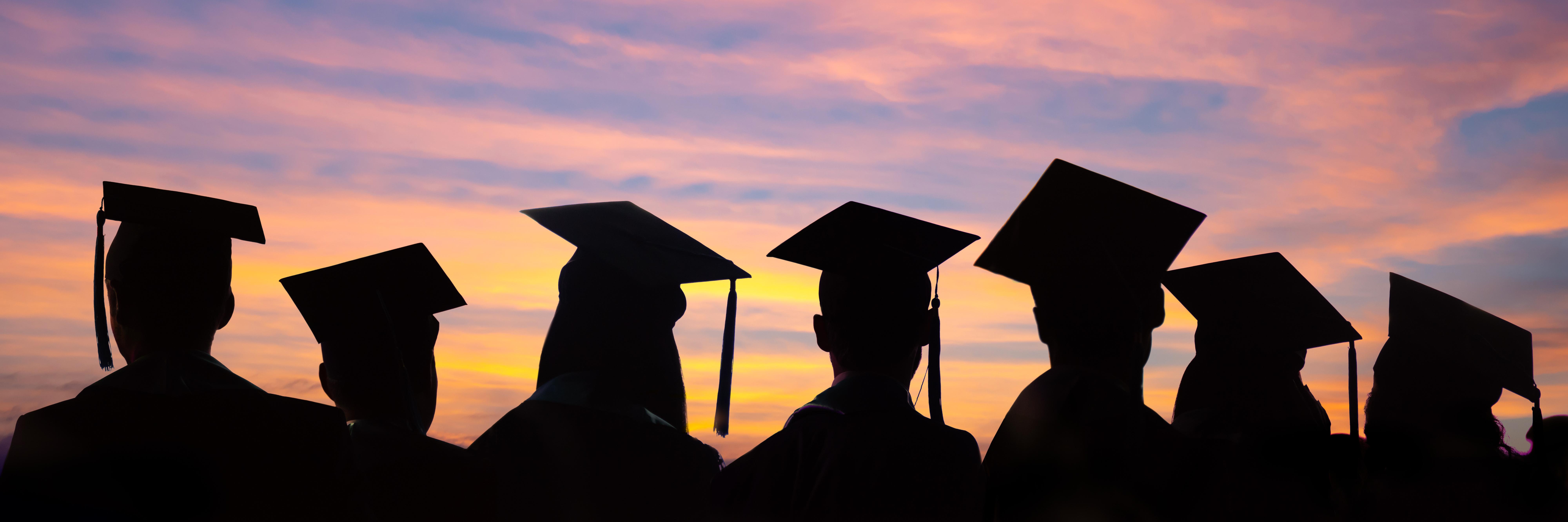 在夕阳的背景下，学生们戴着毕业帽排成一排. 大学毕业典礼的网页横幅.